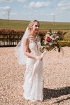 bride in beautiful white dress against lovely Wiltshire landscape with her flower bouquet