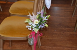 flowers tied to the edge of a chair to decorate the aisle 