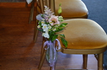 flowers tied to the edge of a chair to decorate the aisle 