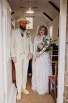 bride and groom standing in the door of the church with her bouquet